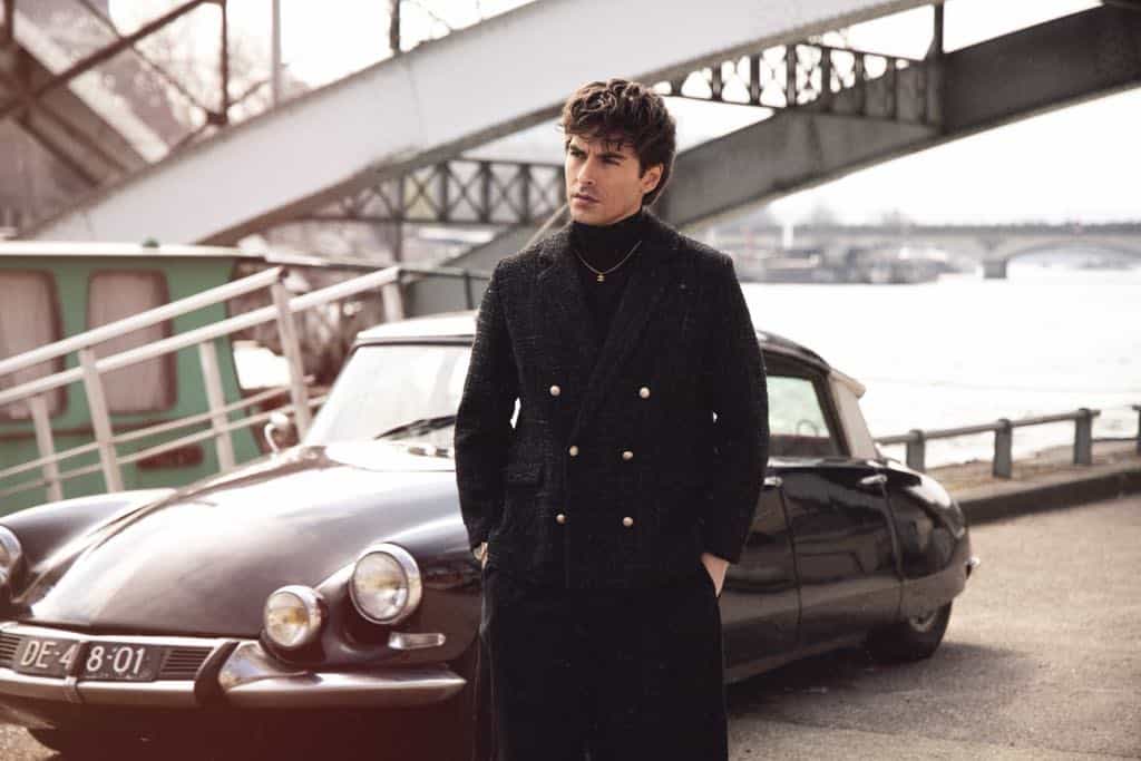 Man standing by vintage car under bridge
